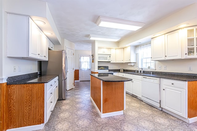 kitchen featuring a sink, white appliances, white cabinets, and a kitchen island