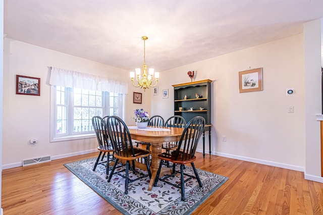 dining room with baseboards, light wood finished floors, a notable chandelier, and visible vents