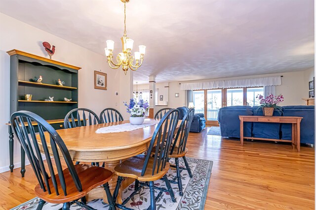dining room with light wood-style flooring and a notable chandelier