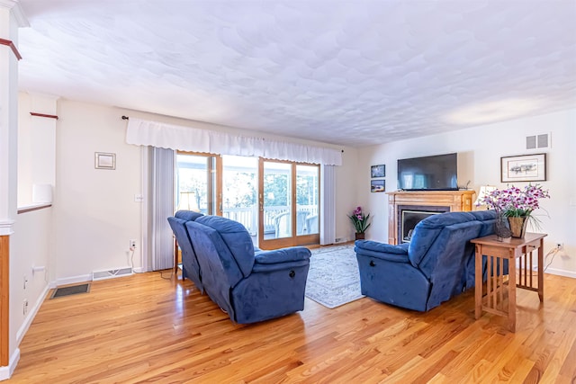 living area featuring a fireplace, visible vents, baseboards, and light wood-style flooring