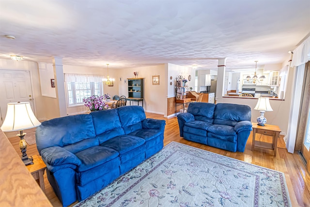 living room with baseboards, an inviting chandelier, and wood finished floors