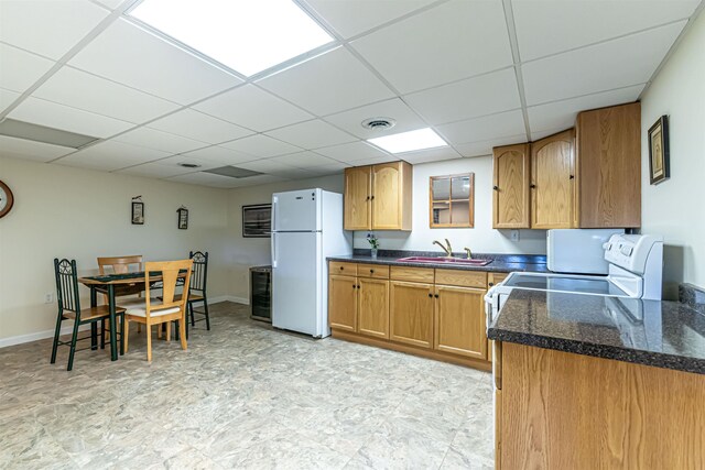 kitchen featuring a sink, freestanding refrigerator, a paneled ceiling, and dark countertops