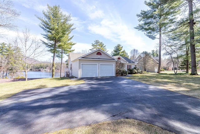 view of side of property with a yard, aphalt driveway, a garage, and a water view