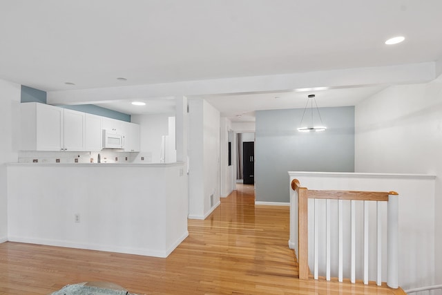 68 Barrington Ave, Nashua, NH 03062 - kitchen featuring white cabinets, white microwave, light wood-type flooring, and baseboards