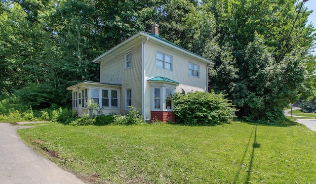 view of front of property featuring a front lawn, a sunroom, and a chimney