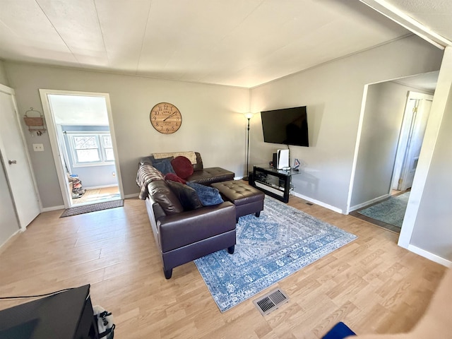 living room featuring visible vents, light wood-type flooring, and baseboards