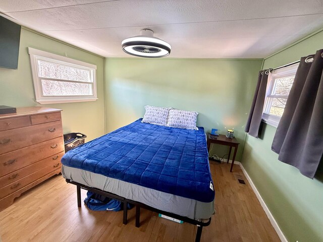 bedroom featuring visible vents, baseboards, and wood finished floors