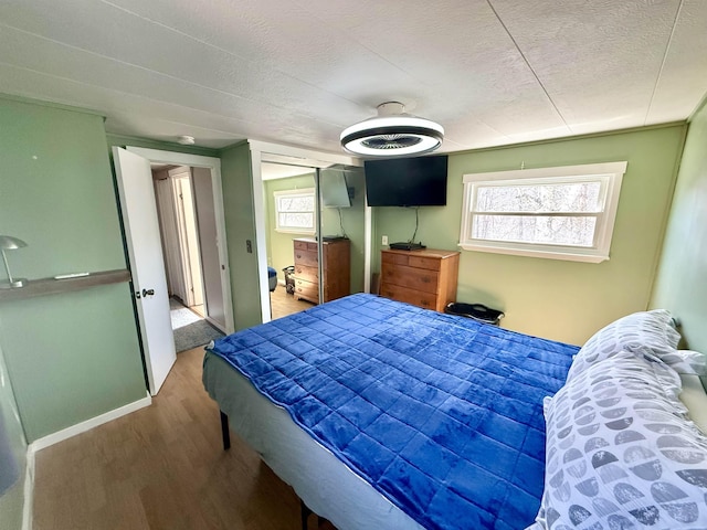 bedroom featuring a closet, a textured ceiling, baseboards, and wood finished floors