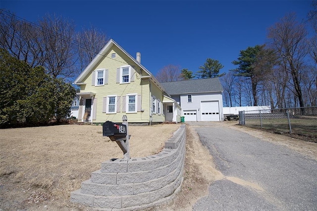 traditional-style house featuring a chimney, fence, a garage, and aphalt driveway