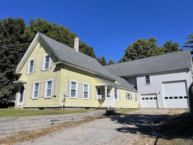 view of front of home with cooling unit, roof with shingles, aphalt driveway, and a garage