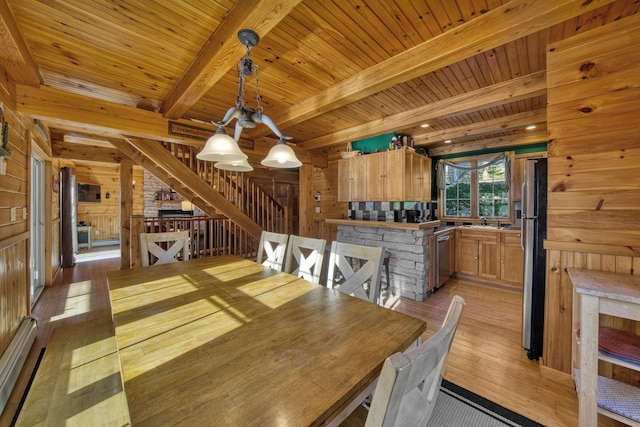 dining room with wood walls, light wood-style floors, and a baseboard radiator