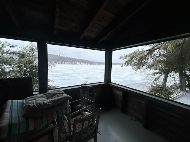 sunroom / solarium with a water view, wooden ceiling, and concrete flooring