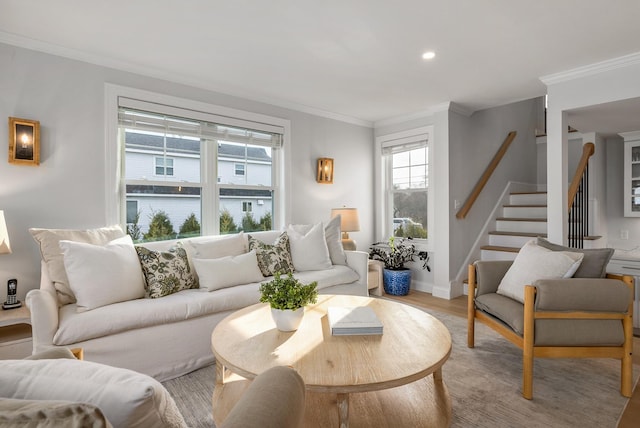 living room featuring light wood-type flooring, baseboards, ornamental molding, and stairway