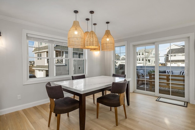 dining area with ornamental molding, baseboards, plenty of natural light, and light wood-style floors