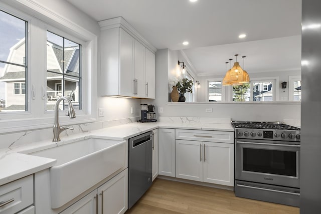 kitchen with a sink, a wealth of natural light, white cabinets, and stainless steel appliances