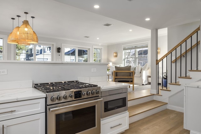 kitchen featuring light stone countertops, light wood-style floors, stainless steel range with gas cooktop, and crown molding