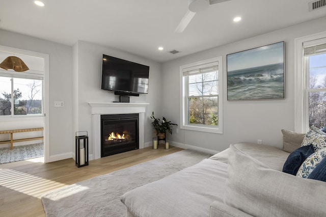 living area featuring visible vents, wood finished floors, and a healthy amount of sunlight