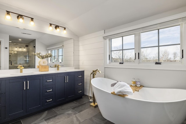 bathroom featuring double vanity, a sink, vaulted ceiling, and a stall shower