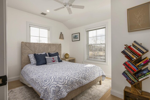 bedroom with ceiling fan, vaulted ceiling, visible vents, wood finished floors, and baseboards