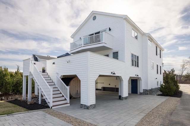 view of front of property featuring an attached garage, stairway, and a balcony