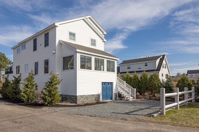 view of property exterior with roof with shingles and stairway