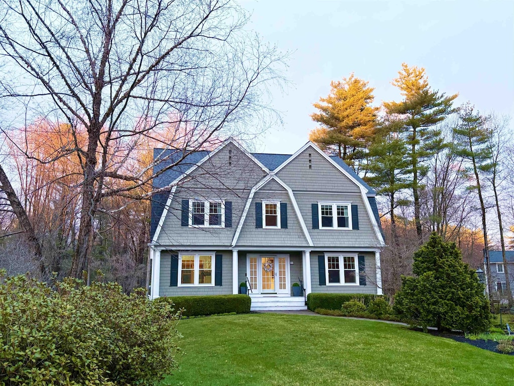 shingle-style home with a gambrel roof and a front lawn