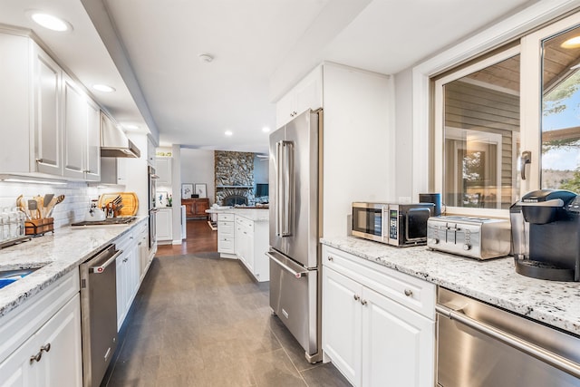 kitchen featuring white cabinets, appliances with stainless steel finishes, backsplash, a toaster, and light stone counters