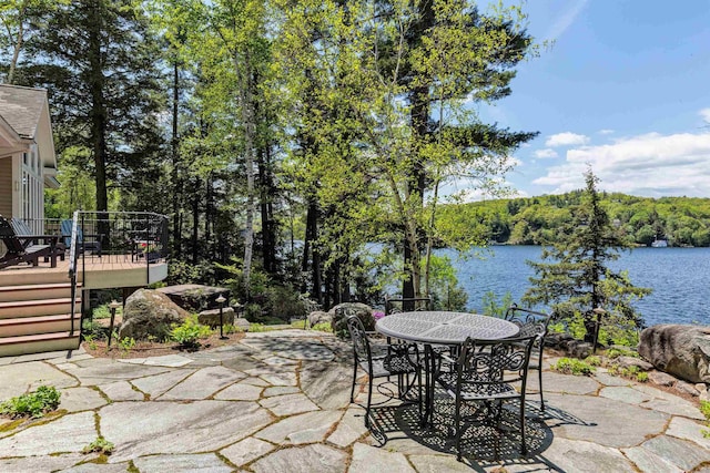 view of patio with outdoor dining space and a deck with water view