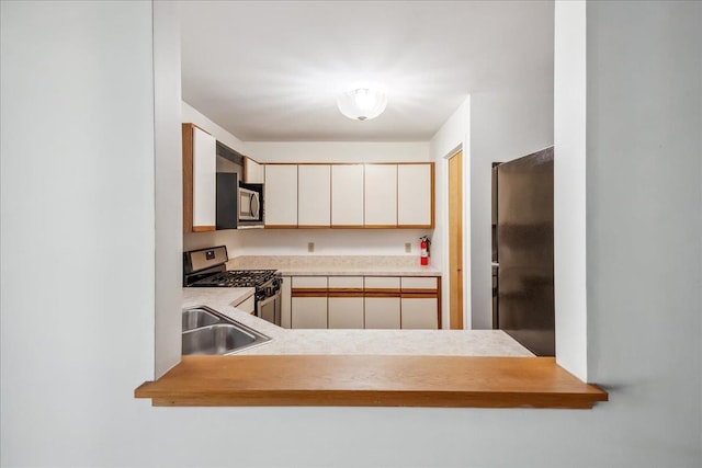 kitchen featuring stainless steel appliances, light countertops, and a sink