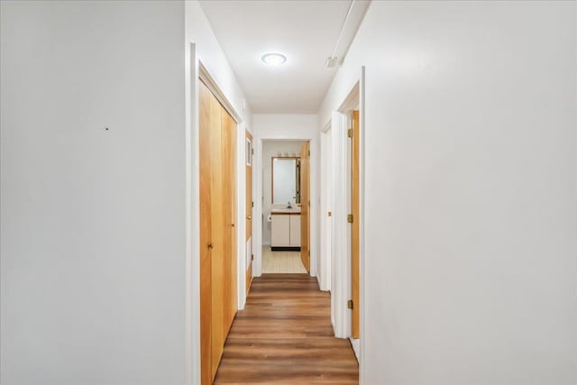 hallway featuring light wood-style flooring and baseboards