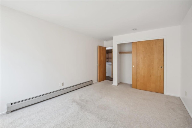 unfurnished bedroom with a baseboard heating unit, washer / clothes dryer, carpet flooring, and a closet