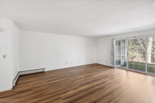 spare room featuring baseboards, wood finished floors, and a baseboard radiator