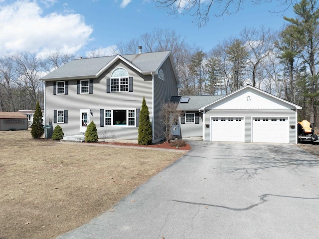 colonial home featuring driveway, a garage, and a front lawn