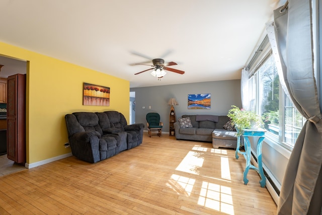 living area featuring a ceiling fan, light wood-type flooring, and baseboards