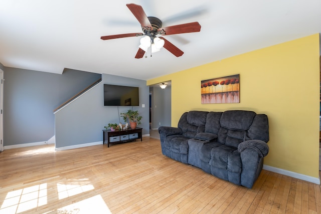 living room with light wood finished floors, ceiling fan, and baseboards