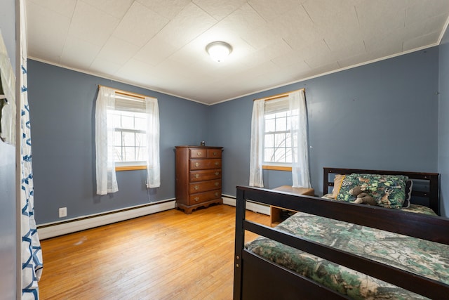 bedroom featuring a baseboard heating unit, ornamental molding, and wood finished floors
