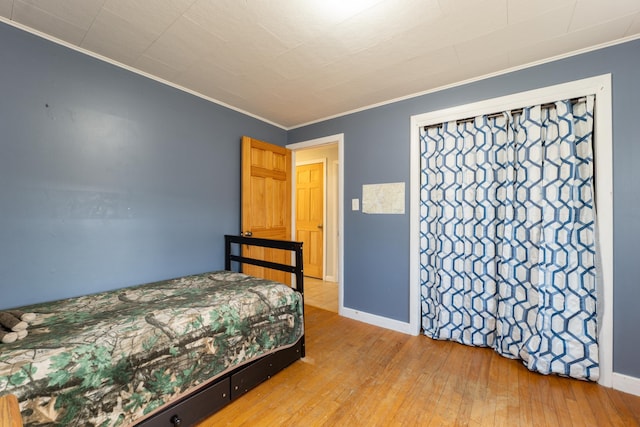 bedroom with crown molding, wood-type flooring, and baseboards