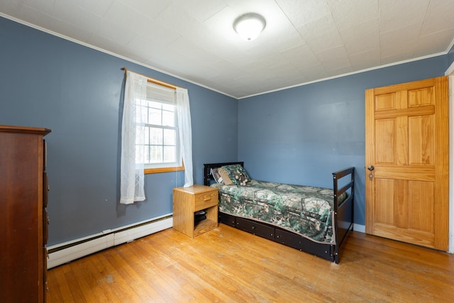 bedroom with a baseboard radiator, crown molding, and hardwood / wood-style flooring