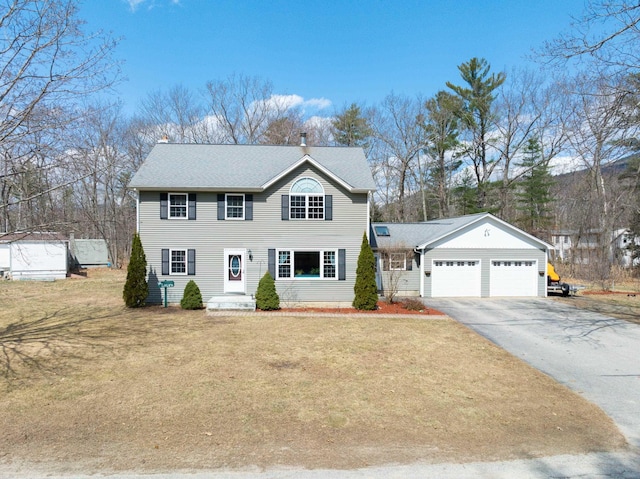 colonial house featuring a garage, a chimney, asphalt driveway, and a front lawn