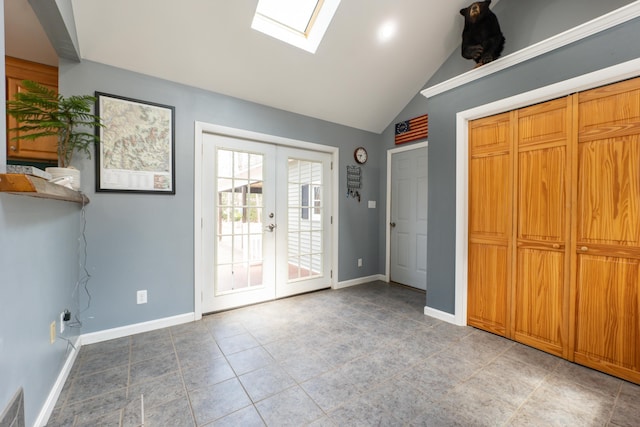 foyer entrance featuring a skylight, french doors, baseboards, light tile patterned flooring, and high vaulted ceiling