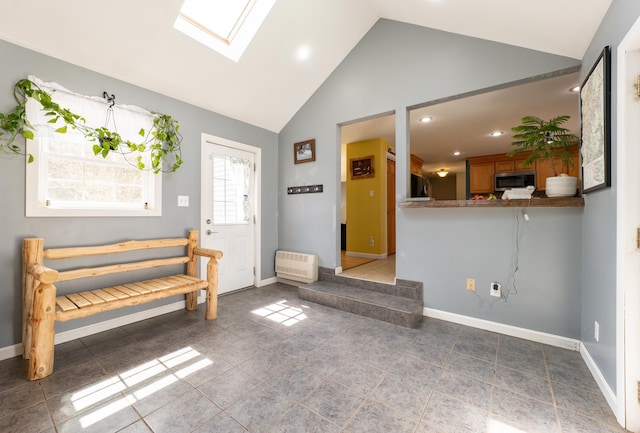 foyer featuring a skylight, baseboards, high vaulted ceiling, recessed lighting, and heating unit