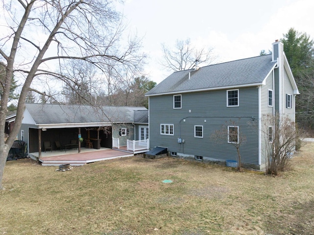 back of property with a deck, a lawn, a chimney, and roof with shingles