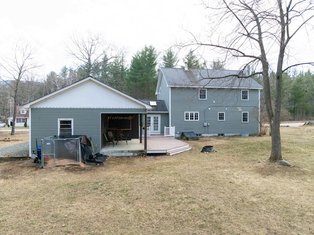 rear view of property featuring a lawn, a deck, and french doors