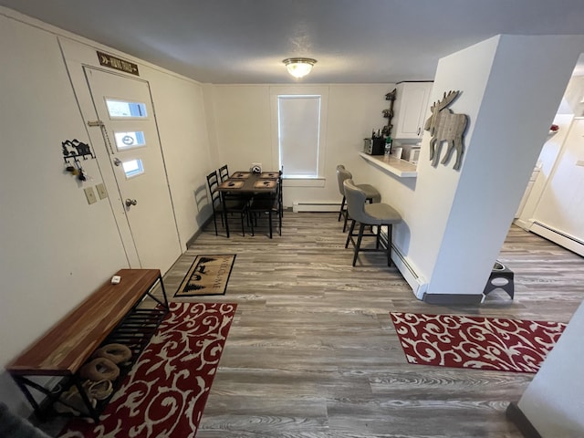 foyer entrance featuring a baseboard heating unit and wood finished floors