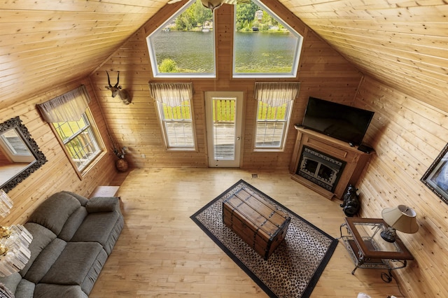 living area with high vaulted ceiling, light wood-style flooring, wood ceiling, a fireplace, and wood walls