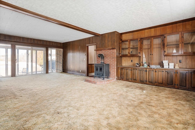 33 Bunker Hill Rd, Auburn, NH 03032 - unfurnished living room with wood walls, carpet flooring, a wood stove, and beamed ceiling