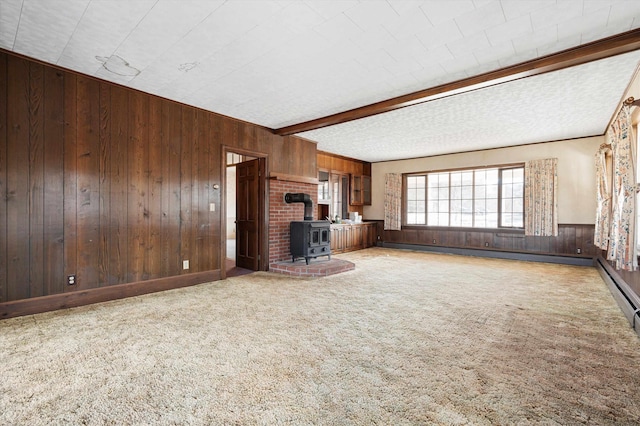 33 Bunker Hill Rd, Auburn, NH 03032 - unfurnished living room featuring wooden walls, a wood stove, baseboard heating, carpet floors, and beam ceiling