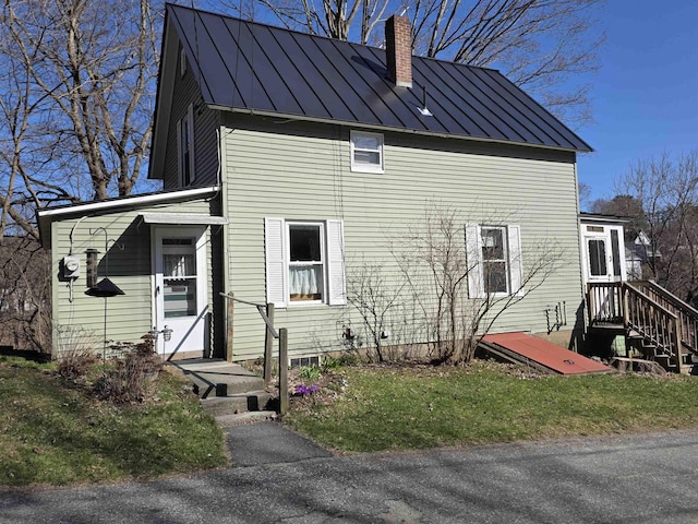 back of property with a chimney, a standing seam roof, and metal roof