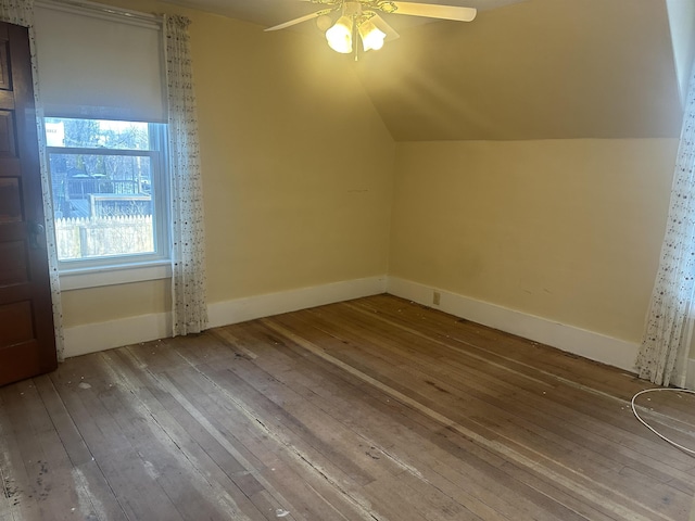 additional living space featuring lofted ceiling, hardwood / wood-style floors, a ceiling fan, and baseboards