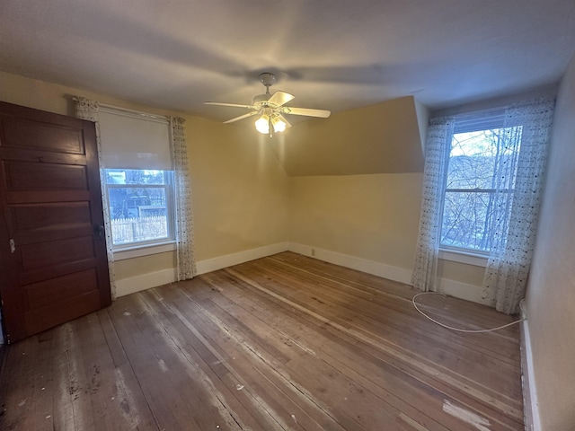 additional living space featuring hardwood / wood-style floors, a healthy amount of sunlight, a ceiling fan, and baseboards